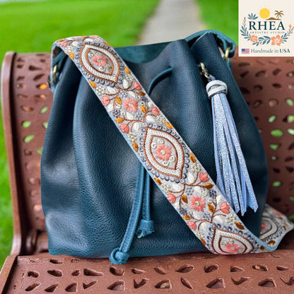 Rhea Artistry Studio 2-inch wide crossbody strap with embroidered floral panels and geometric frames, featuring coral pink flowers and grey backing.
