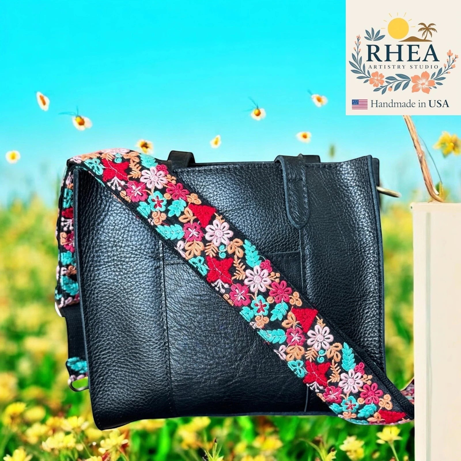 Rhea Artistry Studio black leather crossbody bag with a 2-inch wide adjustable embroidered strap featuring colorful floral lace ribbons.