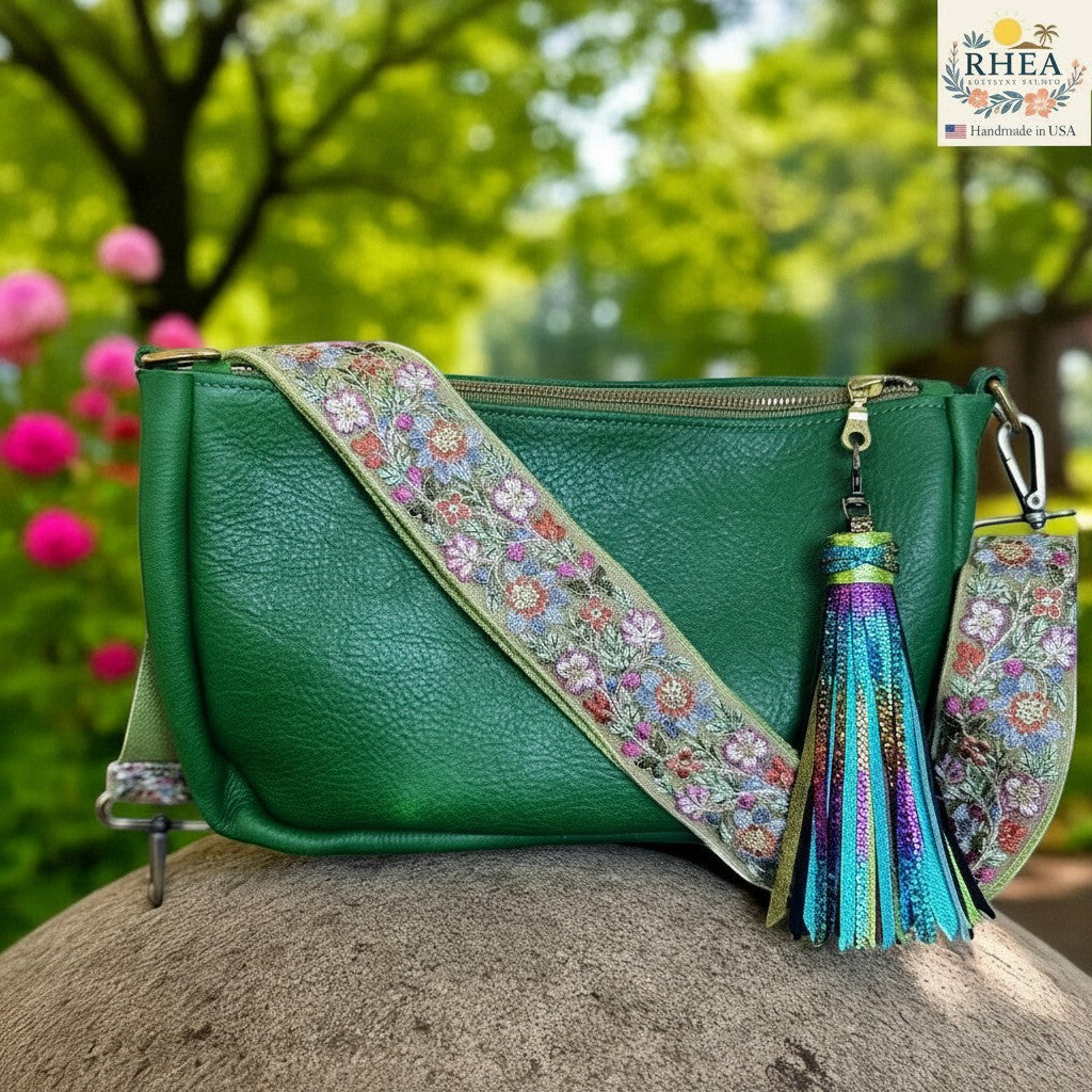 Rhea Artistry Studio green leather crossbody bag with a 2-inch adjustable floral embroidered lace strap and a colorful tassel.