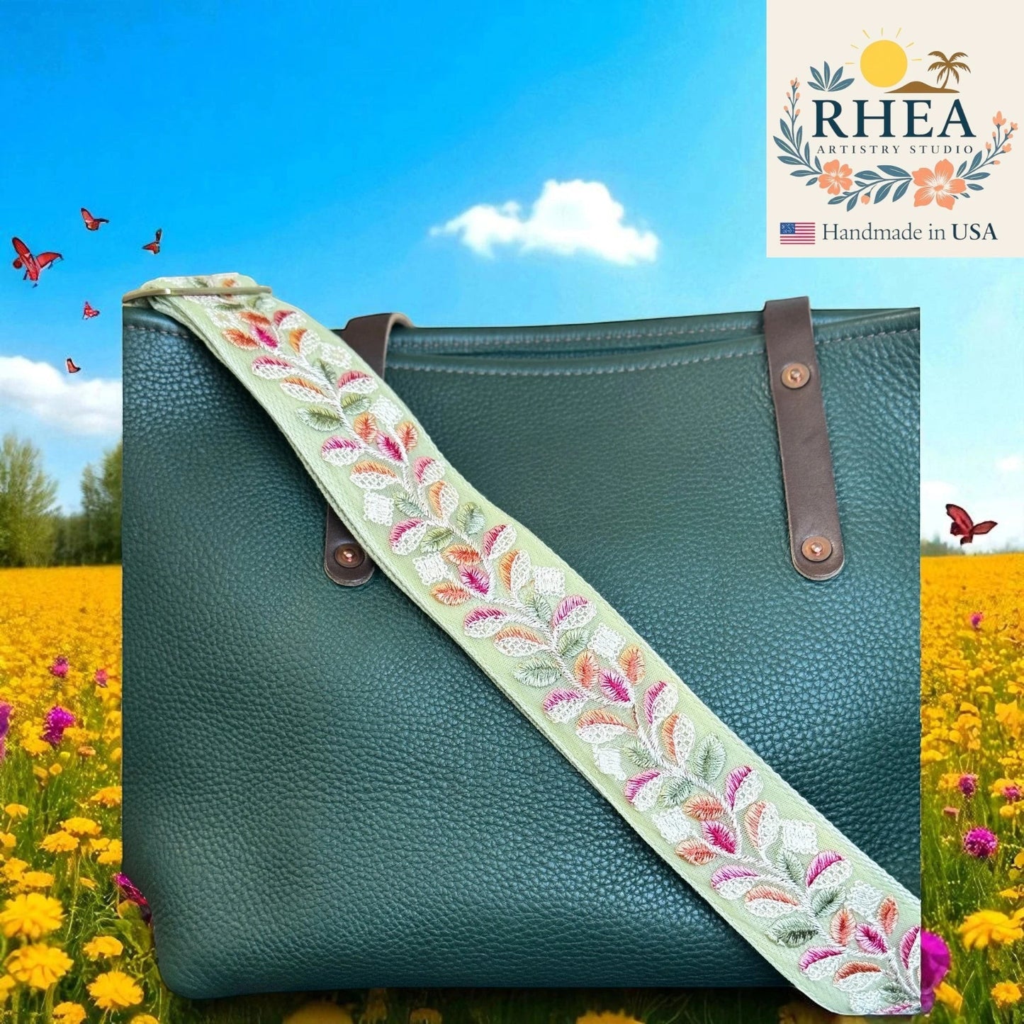 Rhea Artistry Studio light green embroidered crossbody strap with floral leaf pattern and brushed brass hardware on a dark green pebbled leather tote bag.