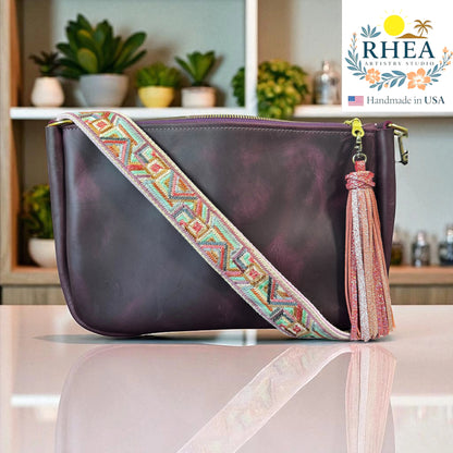 Rhea Artistry Studio 1.5-inch crossbody strap with geometric embroidery in pastel colors, featuring a pink glitter tassel and brushed brass hardware.
