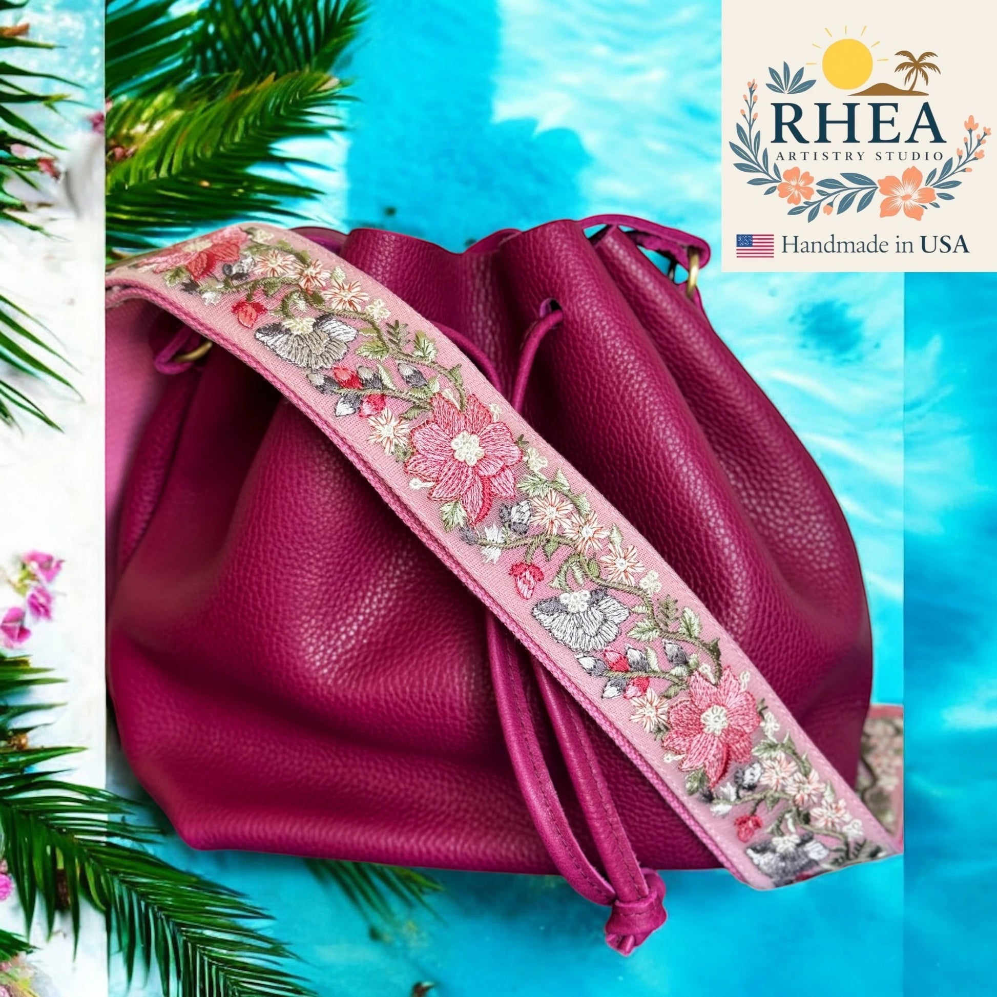 Rhea Artistry Studio pink embroidered crossbody strap with floral pattern on a magenta leather bucket bag.
