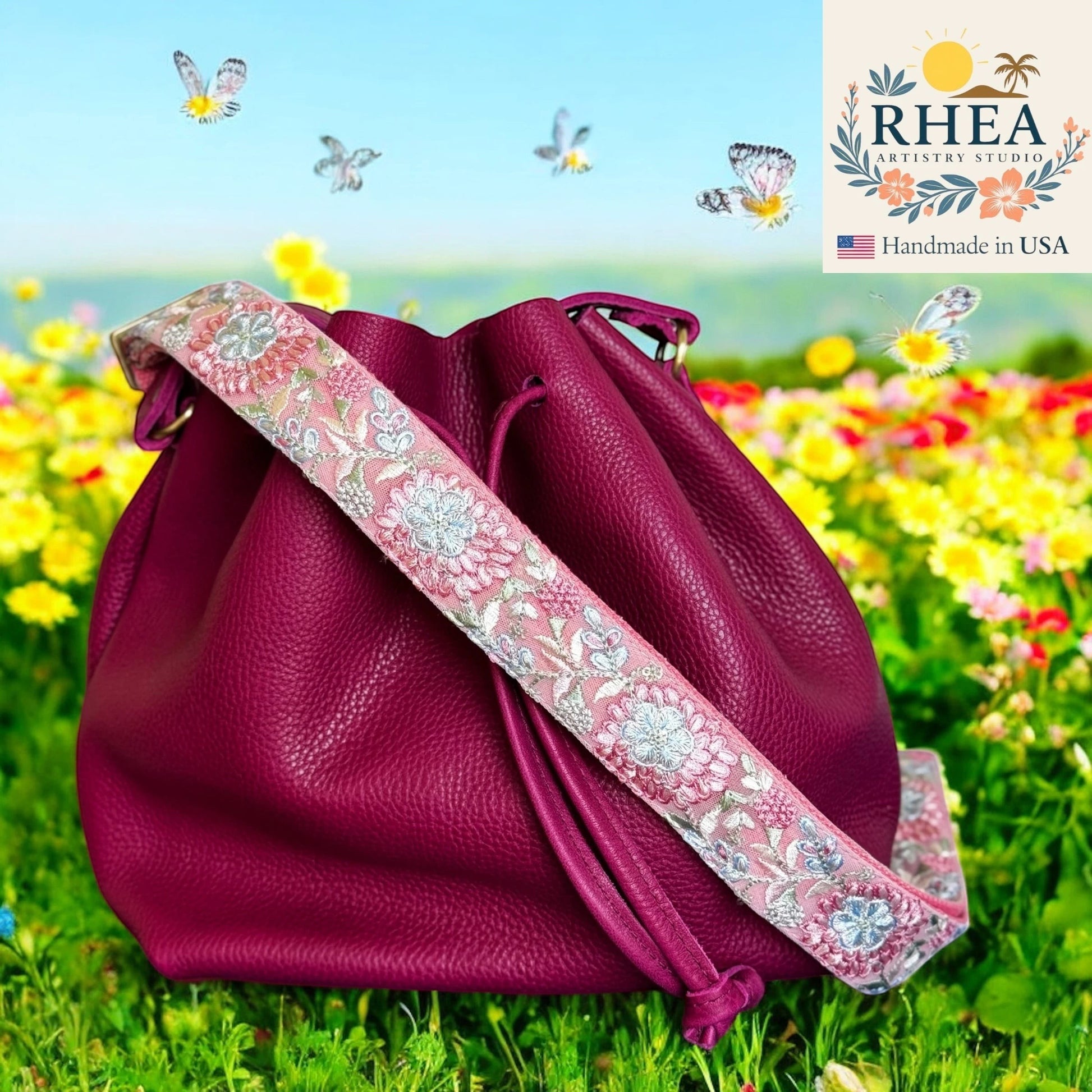 Rhea Artistry Studio 1.5-inch crossbody strap with frosted pink and silver floral embroidery on a magenta leather bucket bag.