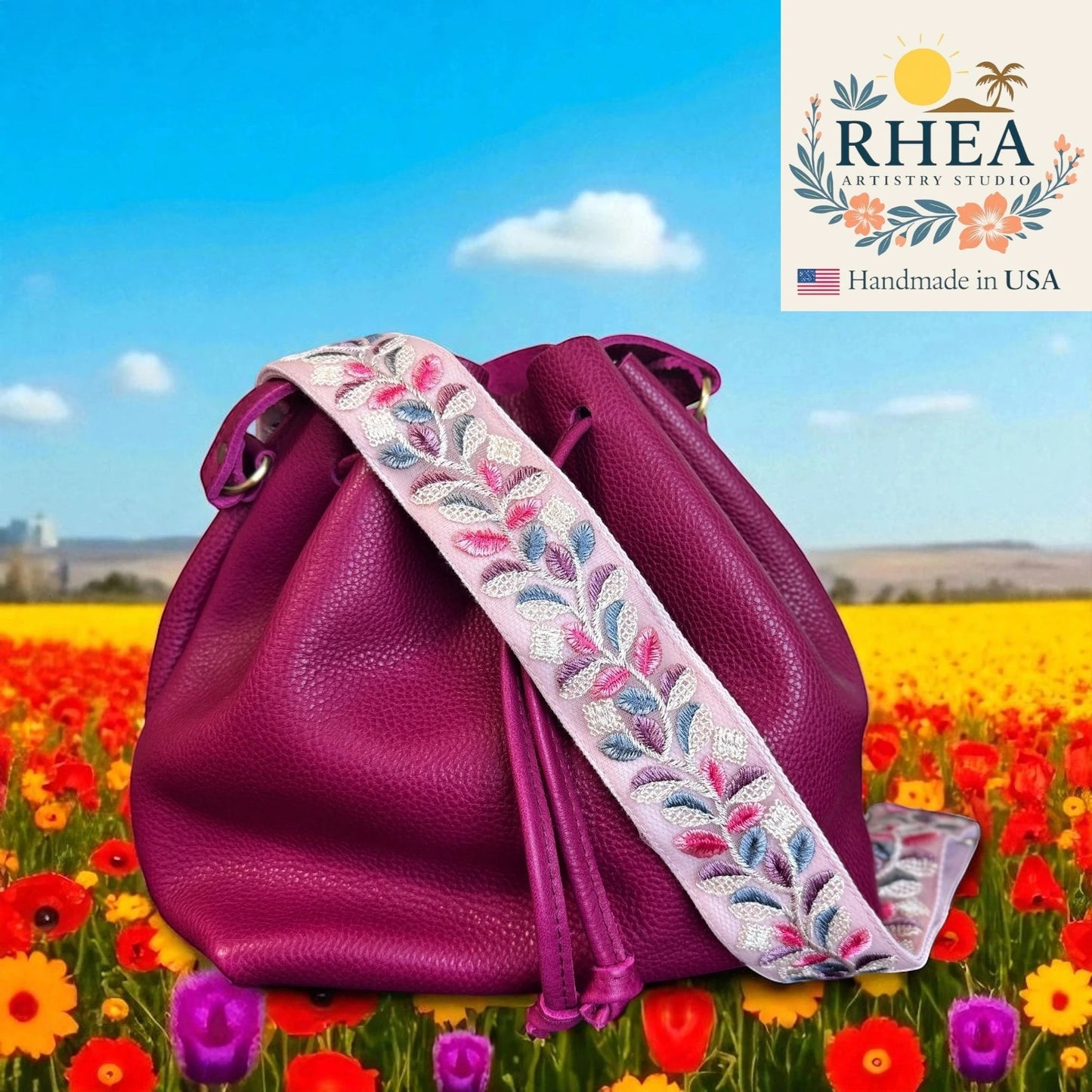 Rhea Artistry Studio 2-inch crossbody strap with pink lace embroidery and colorful leaves, attached to a magenta bucket bag.