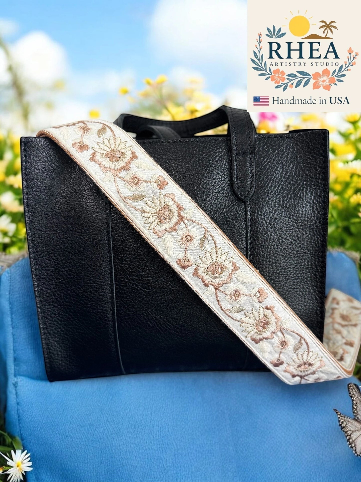 Rhea Artistry Studio cream crossbody strap with floral embroidery in tan and brown, 2-inch width, adjustable length, brushed brass hardware.