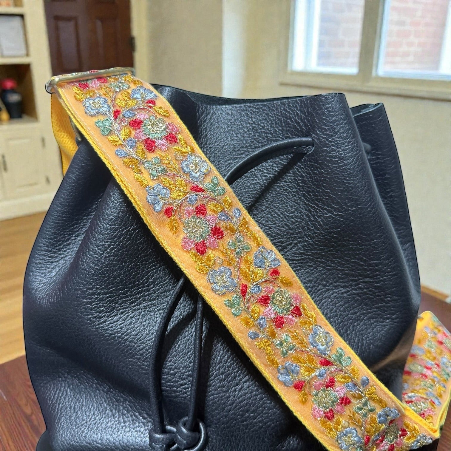 Rhea Artistry Studio 2-inch adjustable crossbody strap with vibrant floral embroidery on a yellow lace ribbon, backed with cotton webbing.