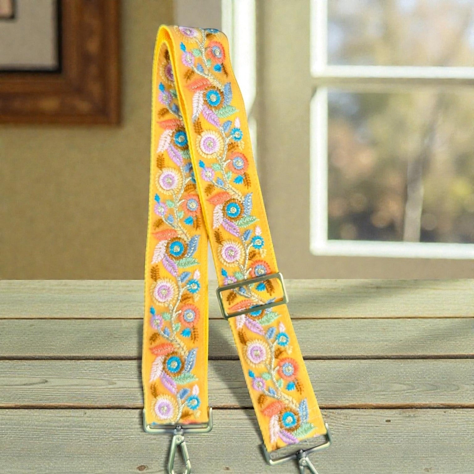 Rhea Artistry Studio yellow crossbody strap with floral embroidery, adjustable length, and brushed brass hardware.