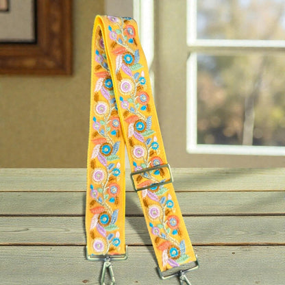 Rhea Artistry Studio yellow crossbody strap with floral embroidery, adjustable length, and brushed brass hardware.
