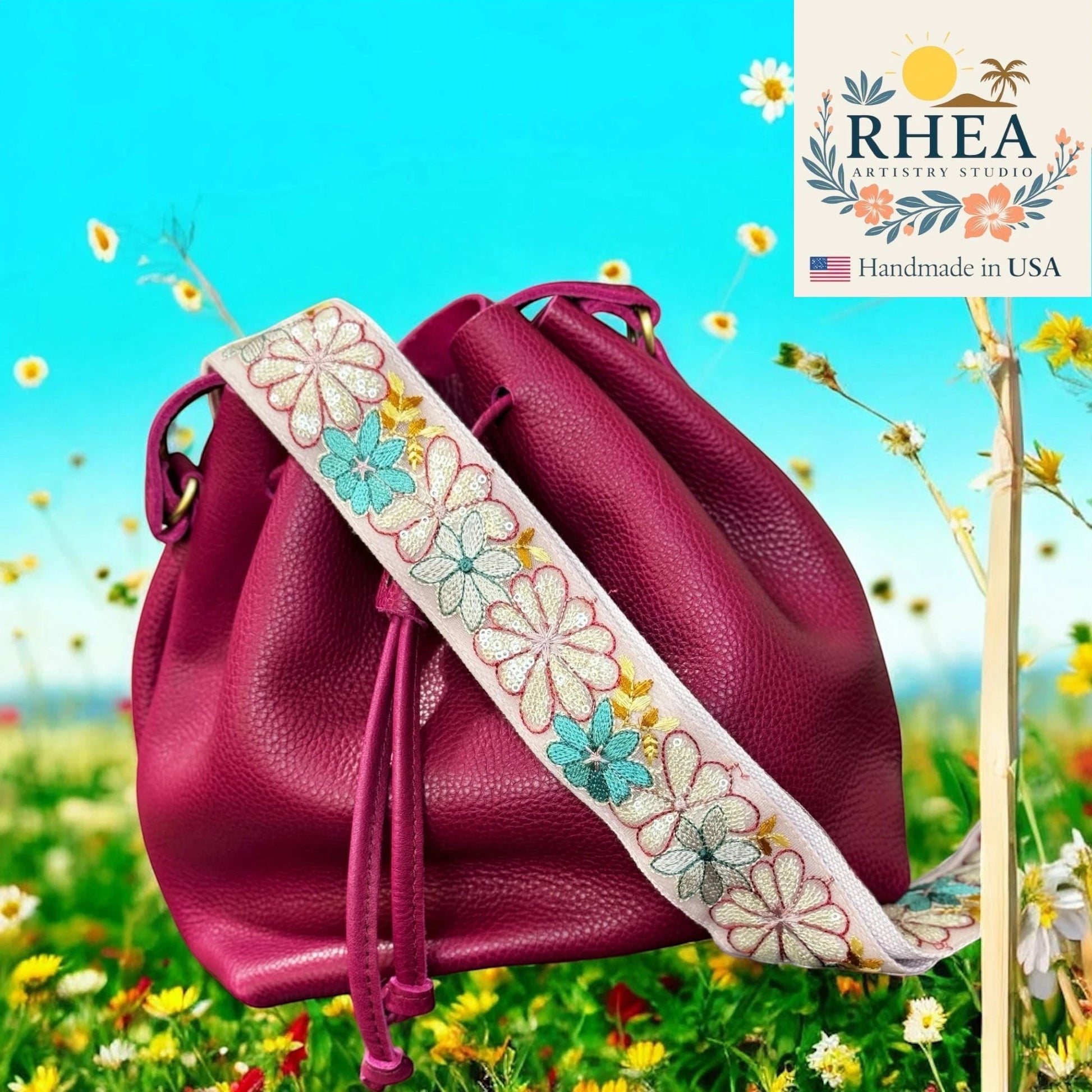 Rhea Artistry Studio 2-inch crossbody strap with embroidered white and blue daisies, made from lace and cotton webbing.