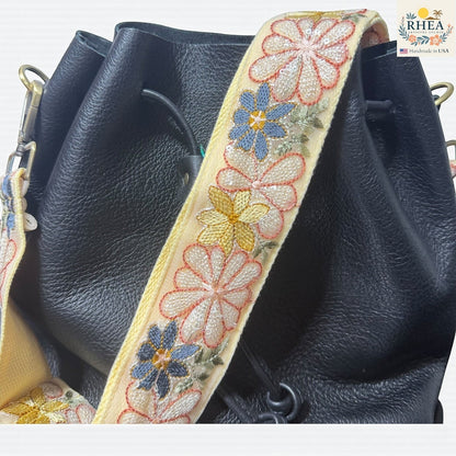 Rhea Artistry Studio 2-inch wide adjustable crossbody strap with embroidered daisies in pink, yellow, and blue on a cream lace ribbon with cotton backing.