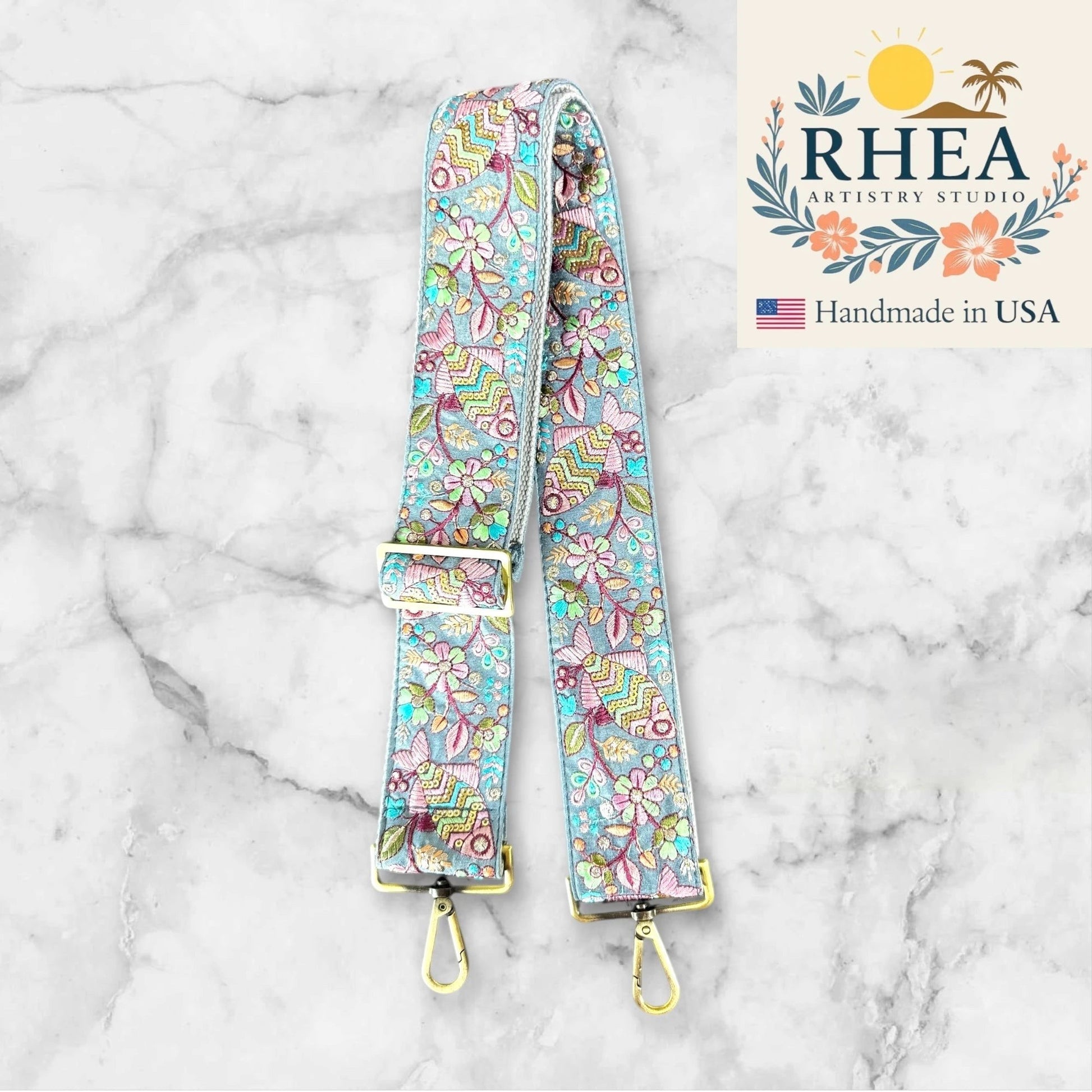 Rhea Artistry Studio 2-inch wide adjustable crossbody strap with embroidered fish and floral lace in pastel colors, brushed brass hardware.