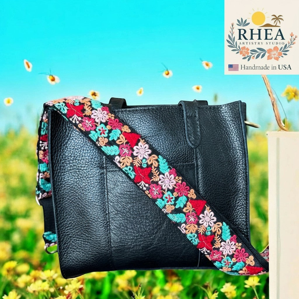 Rhea Artistry Studio 2-inch crossbody strap with colorful floral embroidery on black leather bag.