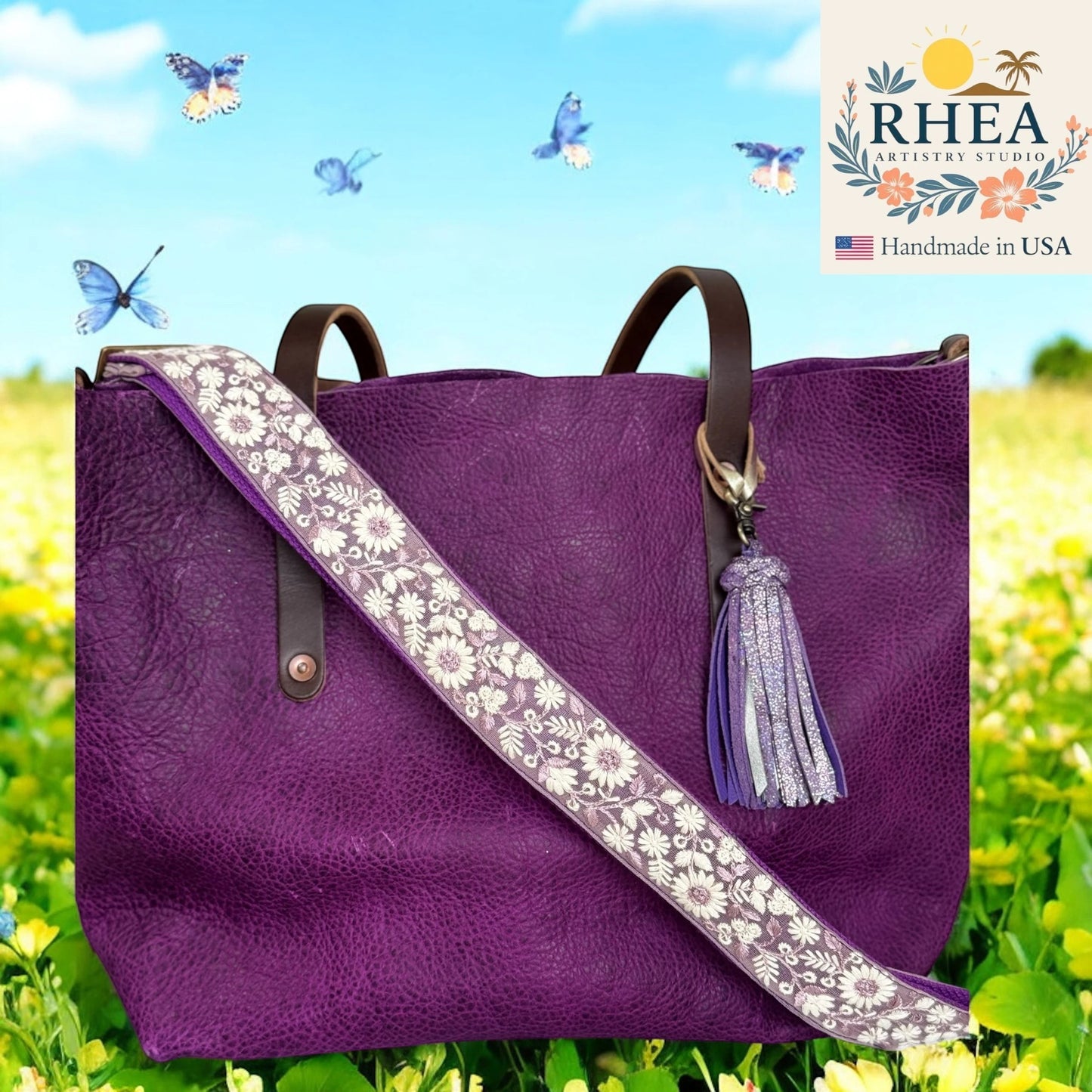 Rhea Artistry Studio purple leather tote bag with a 1.5-inch adjustable crossbody strap featuring white floral embroidery and a purple tassel.