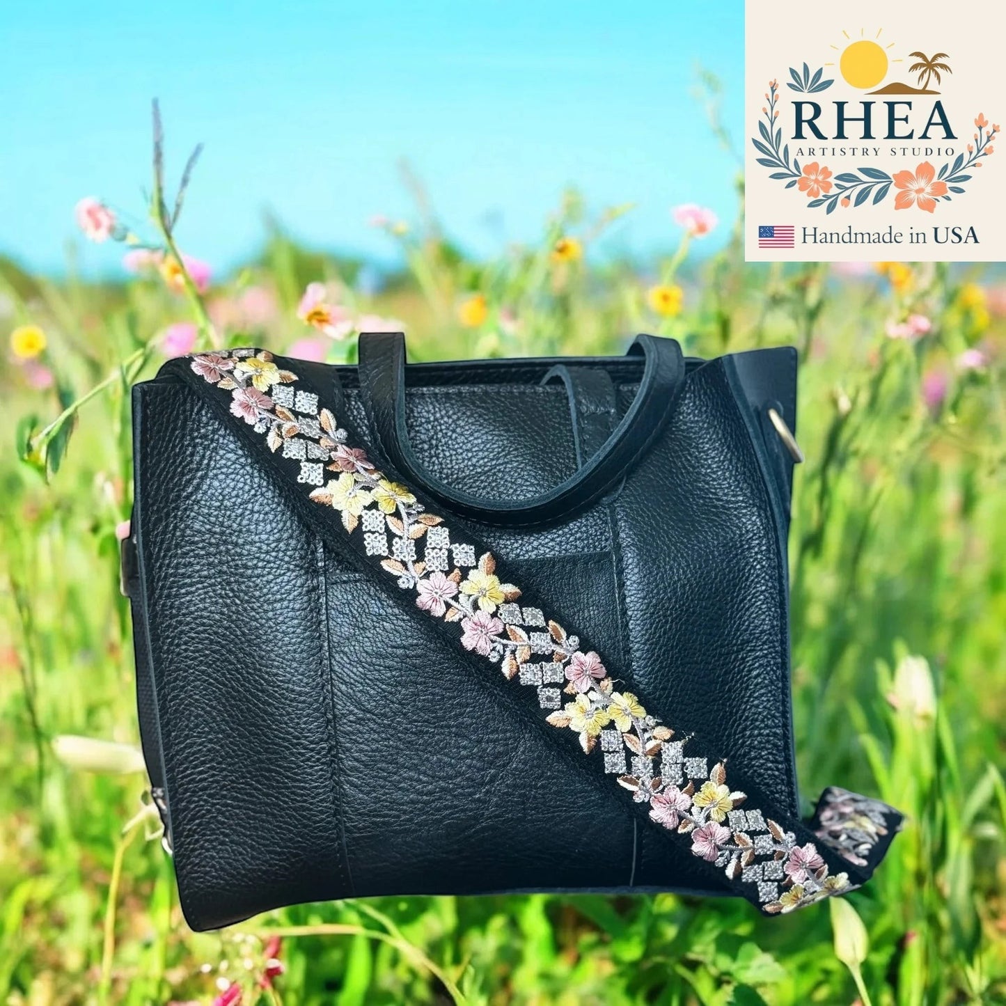Rhea Artistry Studio black crossbody strap with embroidered yellow, pink, and white floral pattern and brushed brass hardware.