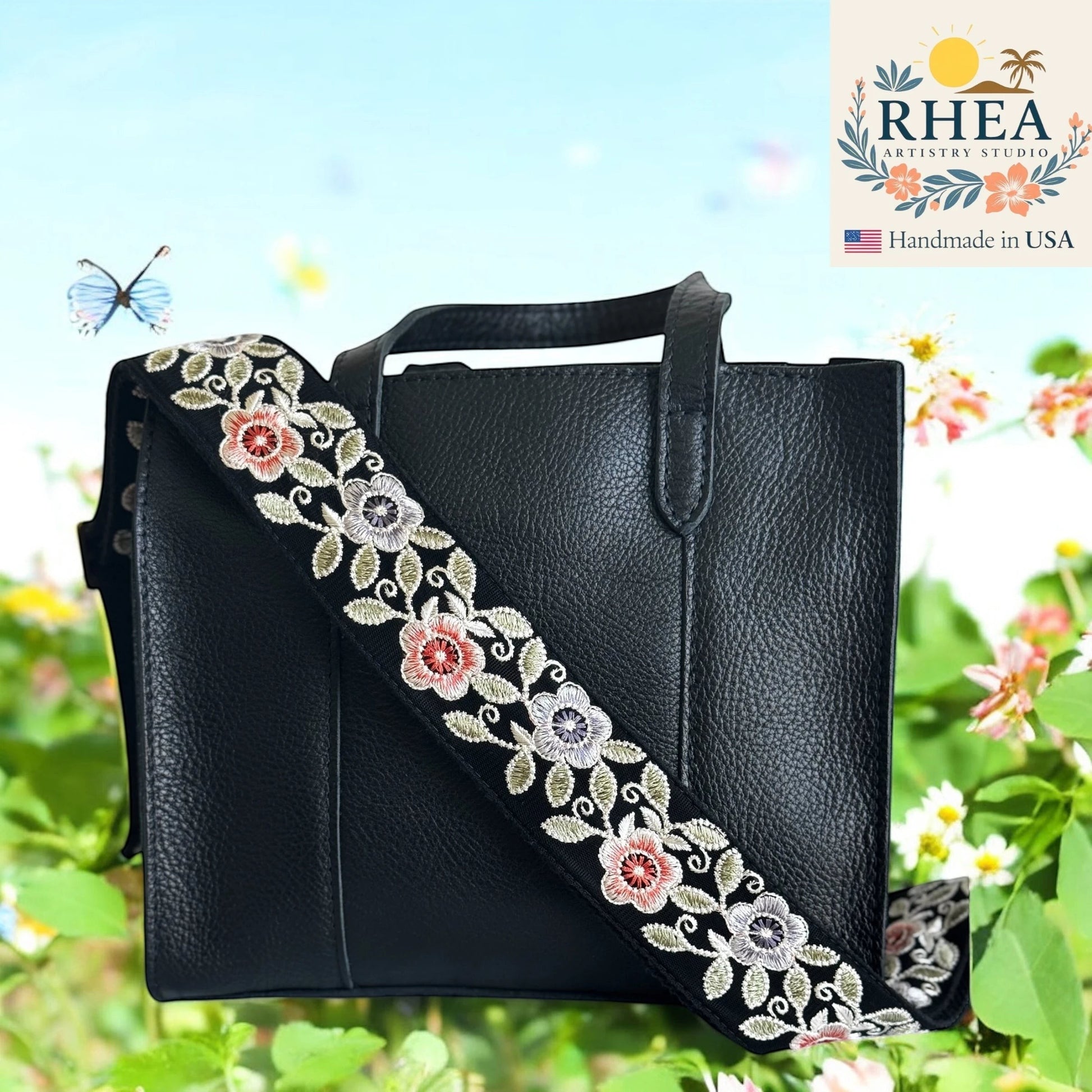 Rhea Artistry Studio 2-inch crossbody strap with embroidered colorful florals on black fabric, adjustable length, brushed brass hardware.