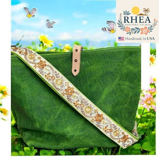 Rhea Artistry Studio 1.5-inch crossbody strap with embroidered floral pattern in tan, gold, and white on a green bag.