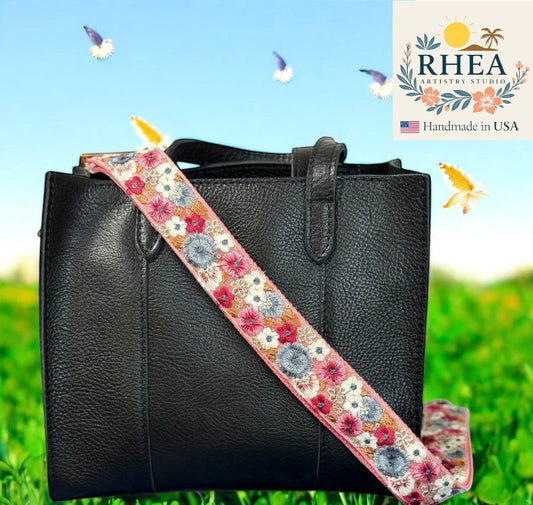 Rhea Artistry Studio pink crossbody strap with embroidered floral pattern in white, blue, and pink, 1.5-inch width, adjustable length.