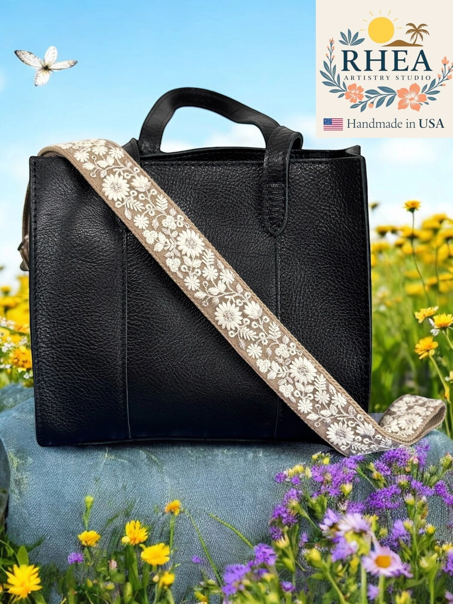 Rhea Artistry Studio adjustable 1.5-inch crossbody strap with white floral embroidery on tan webbing, featuring brushed brass hardware.