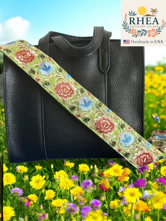 Rhea Artistry Studio 2-inch crossbody strap with green background and embroidered red, blue, and white floral pattern. Adjustable strap with brass hardware.
