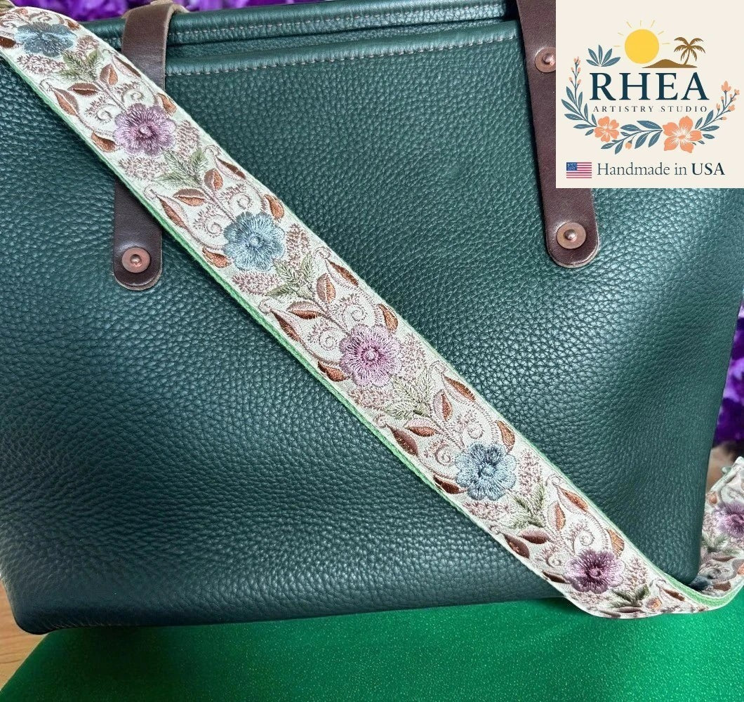 Rhea Artistry Studio embroidered lace and cotton webbing crossbody strap with floral pattern, adjustable 30-54 inches, brushed brass hardware.