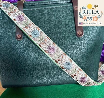 Rhea Artistry Studio embroidered lace and cotton webbing crossbody strap with floral pattern, adjustable 30-54 inches, brushed brass hardware.