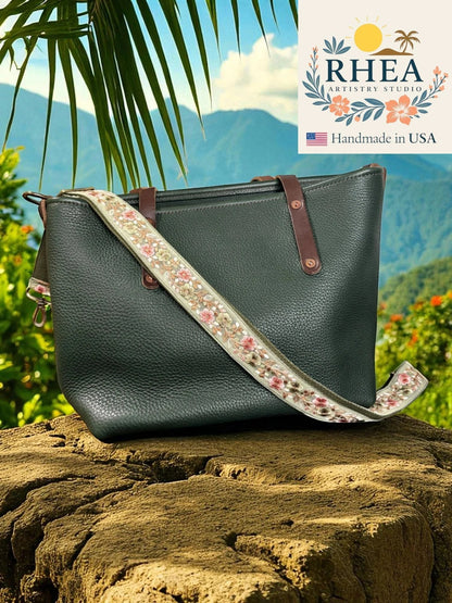 Rhea Artistry Studio 1.5-inch crossbody strap with blush pink and ivory floral embroidery on a light green background, adjustable length.