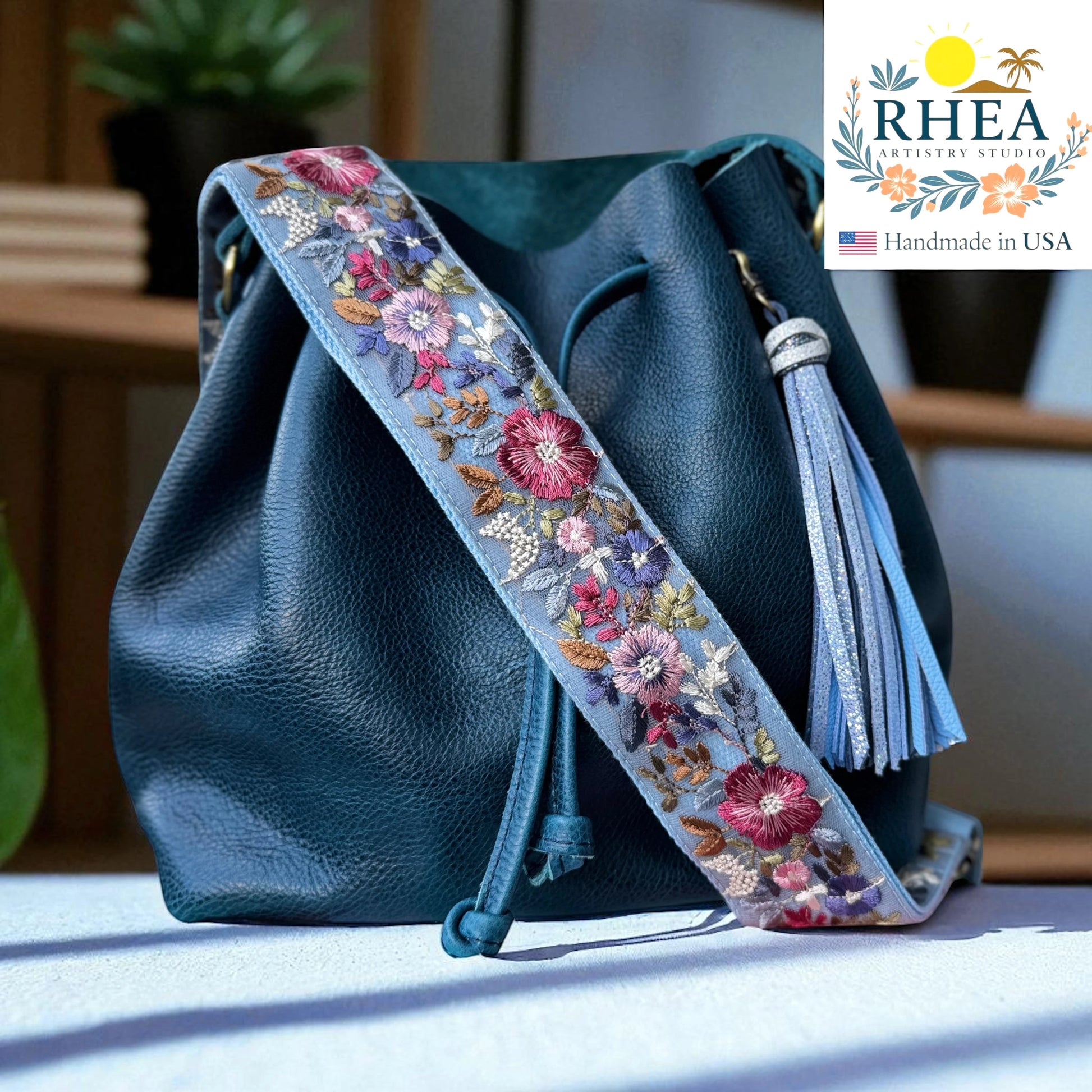 Rhea Artistry Studio light blue crossbody strap with vibrant embroidered floral motifs, 2-inch width, adjustable length.