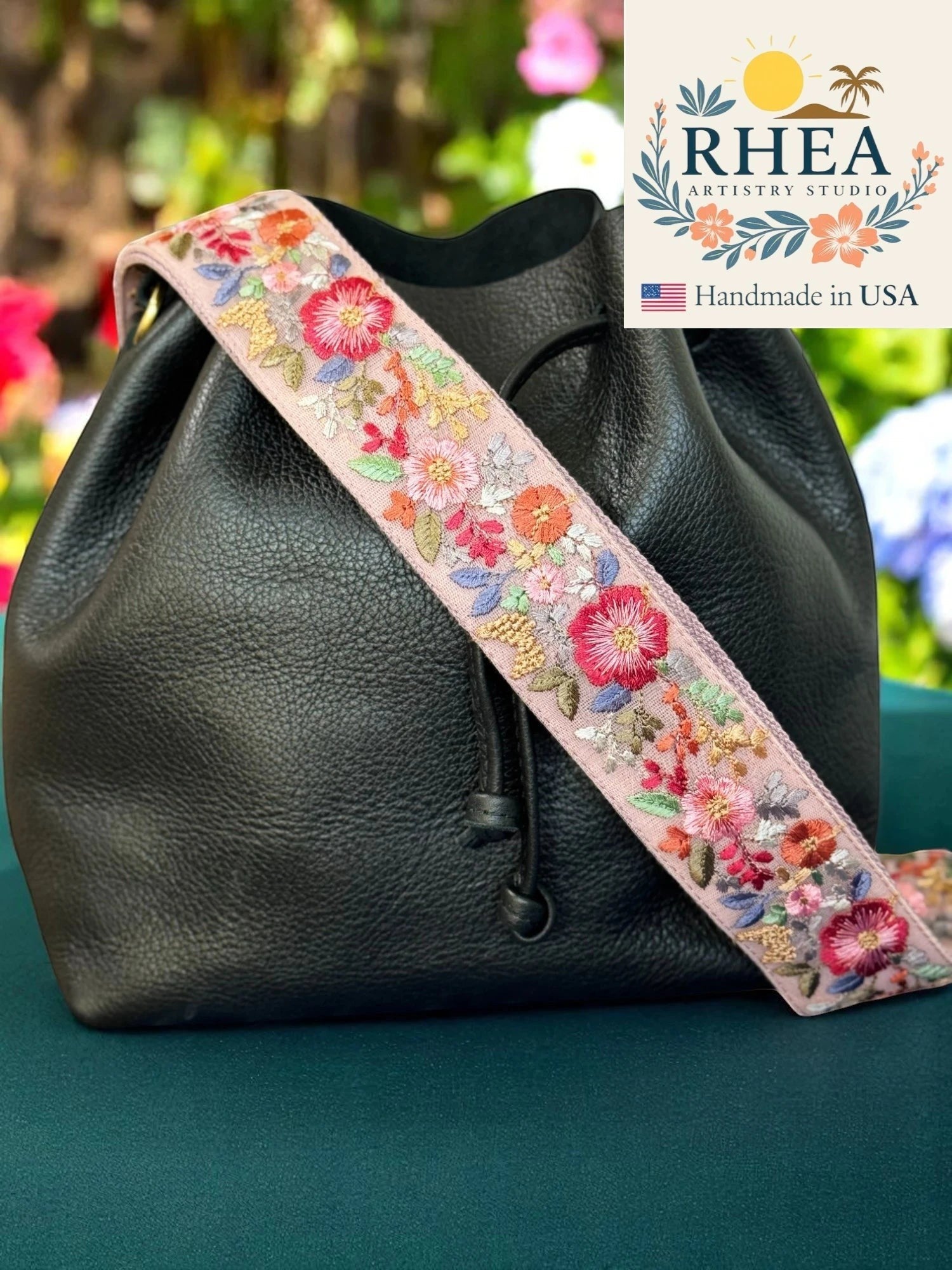 Rhea Artistry Studio pink crossbody strap with embroidered floral details and brushed brass hardware, 2-inch width.
