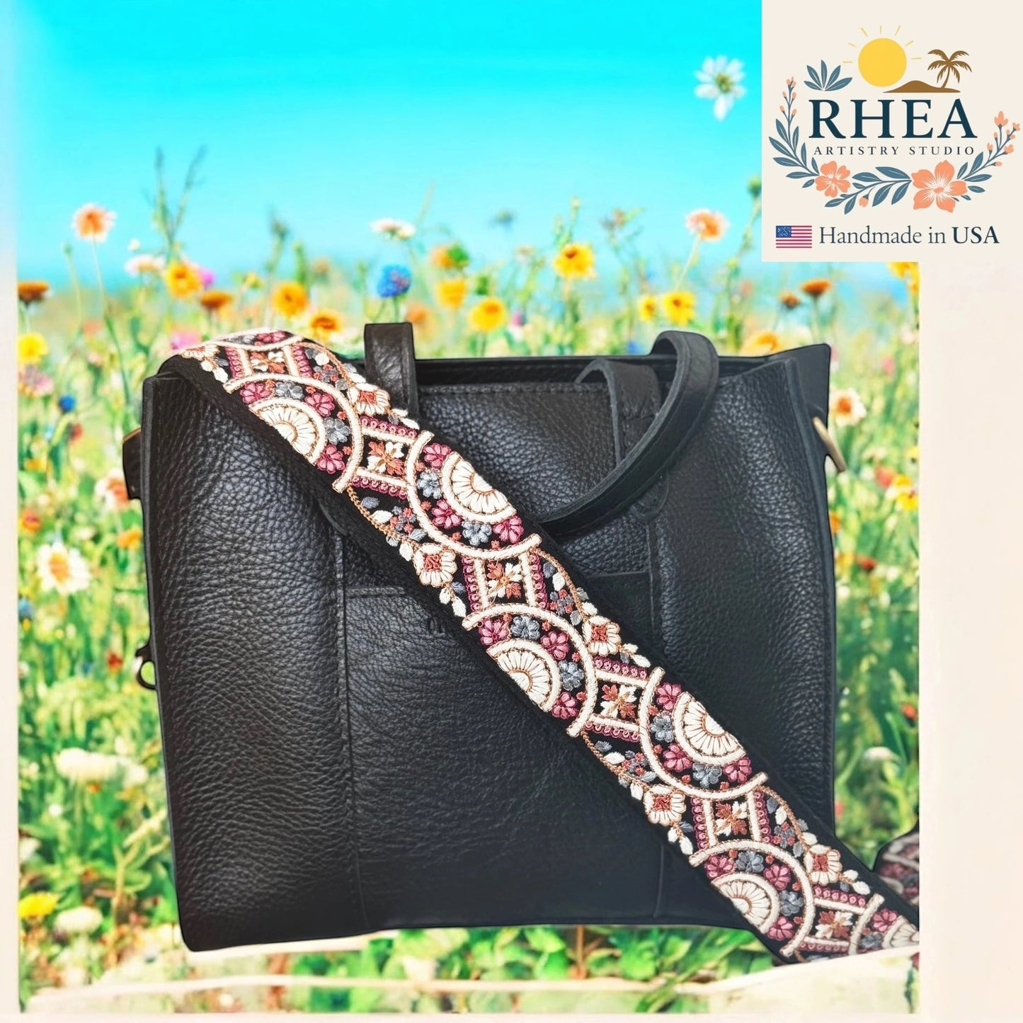 Rhea Artistry Studio 2-inch crossbody strap with embroidered floral lace in pink, white, and grey on black webbing. Adjustable length, brushed brass hardware.