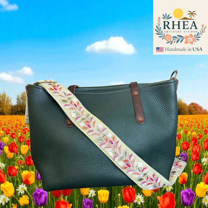 Rhea Artistry Studio 2-inch crossbody strap with embroidered floral lace in pastel colors on light green webbing, adjustable, with brushed brass hardware.