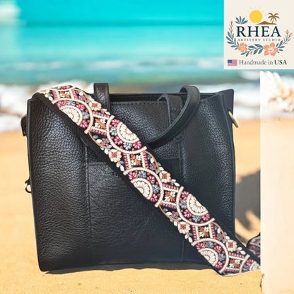 Rhea Artistry Studio 2-inch crossbody strap with embroidered floral lace in pink, white, and grey on black webbing. Adjustable length with brass hardware.