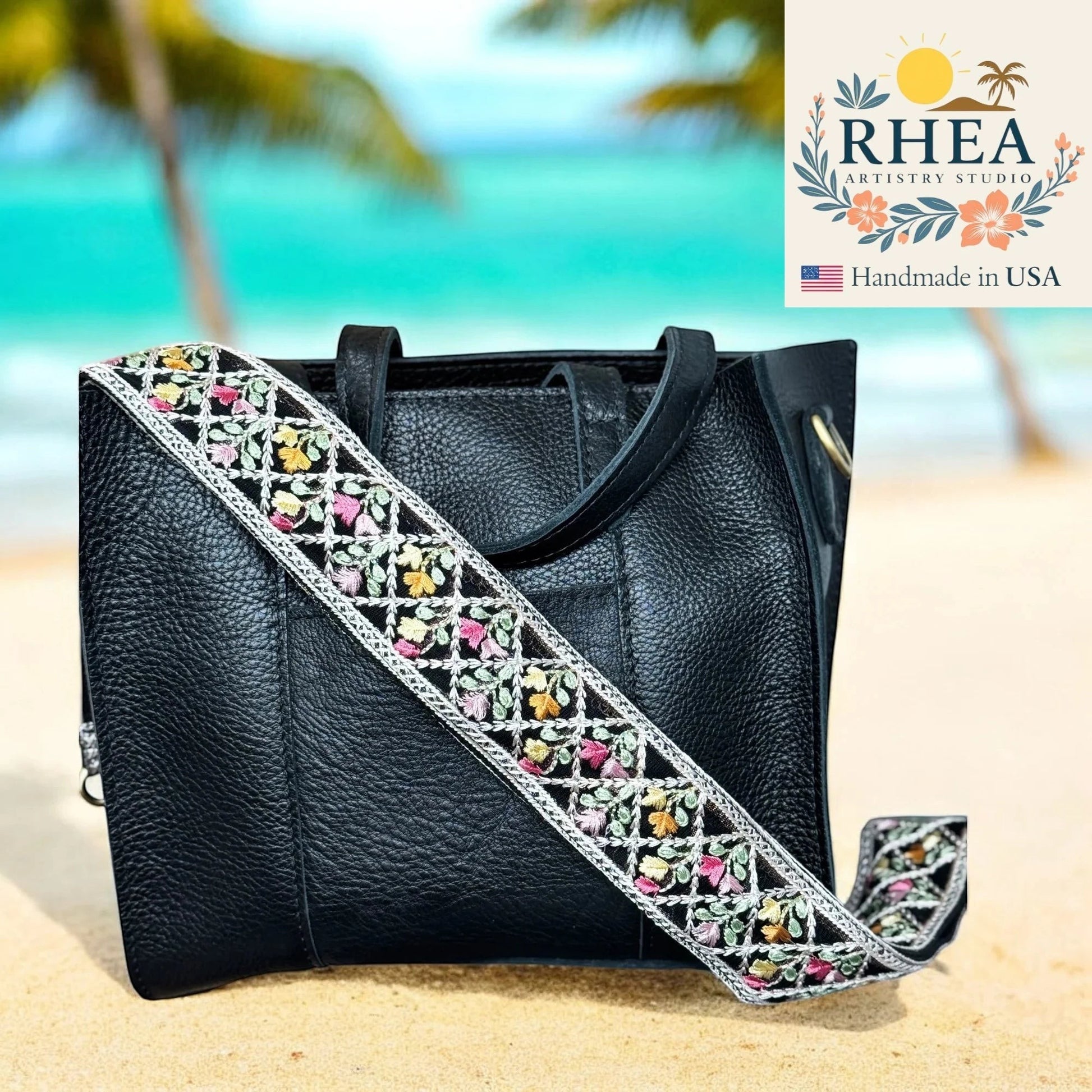 Rhea Artistry Studio black leather handbag with a 2-inch wide crossbody strap featuring embroidered floral lace in pink, yellow, and green.