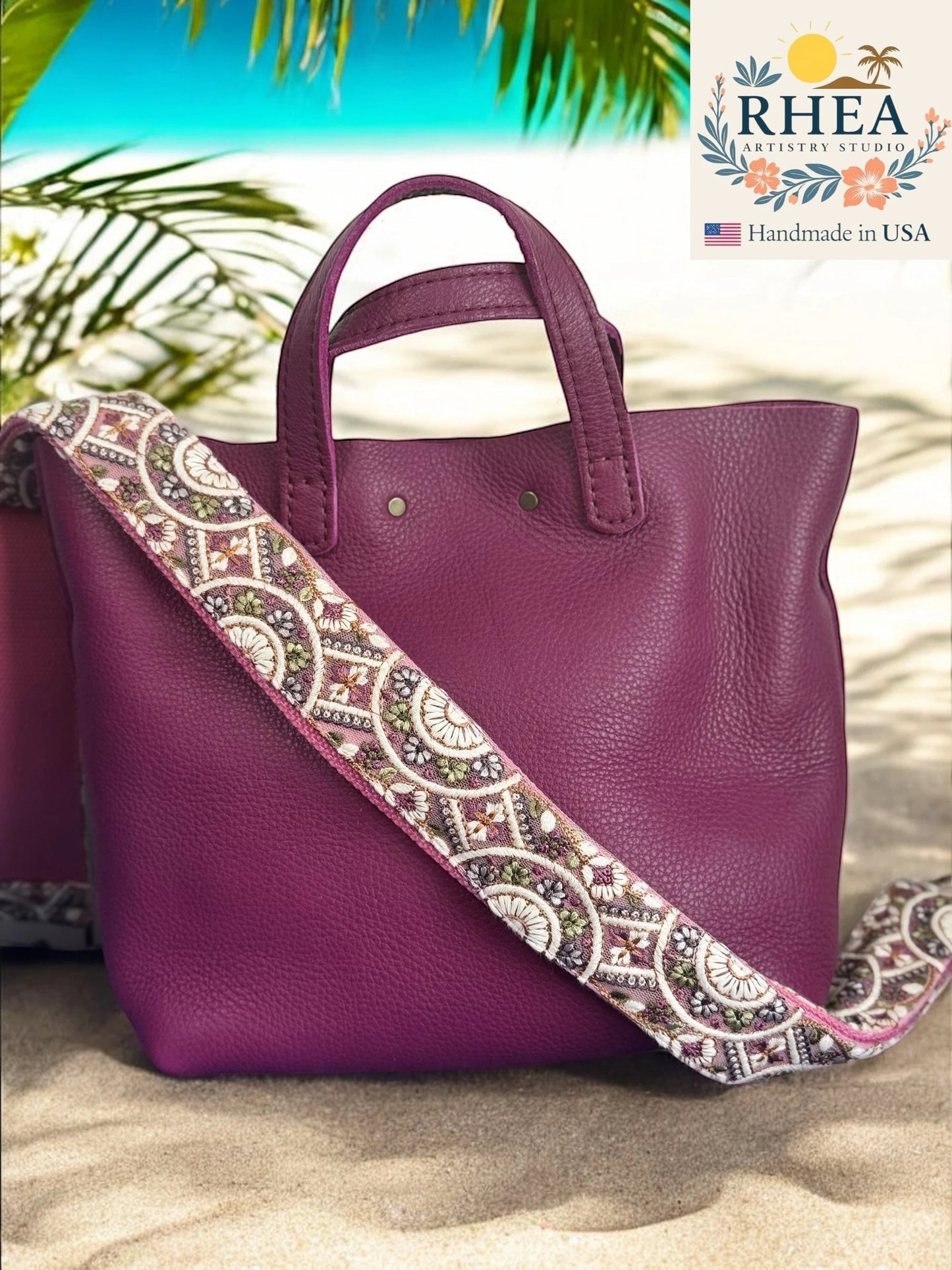 Rhea Artistry Studio 2-inch wide crossbody strap with embroidered floral lace in purple, white, and green. Adjustable strap with brushed brass hardware.