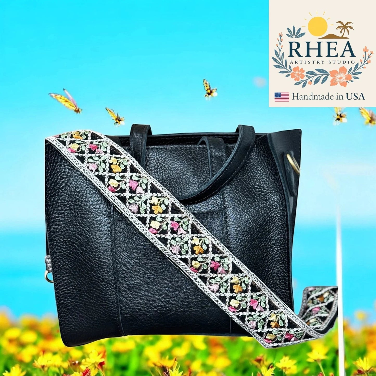 Rhea Artistry Studio black leather handbag with a 2-inch wide embroidered floral lace strap in pastel colors. Adjustable crossbody strap.