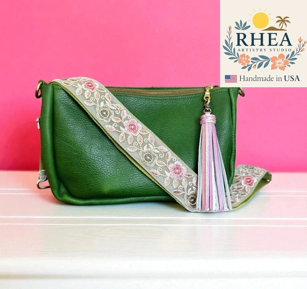 Rhea Artistry Studio green leather crossbody bag with a 2-inch wide embroidered floral strap and pink tassel.