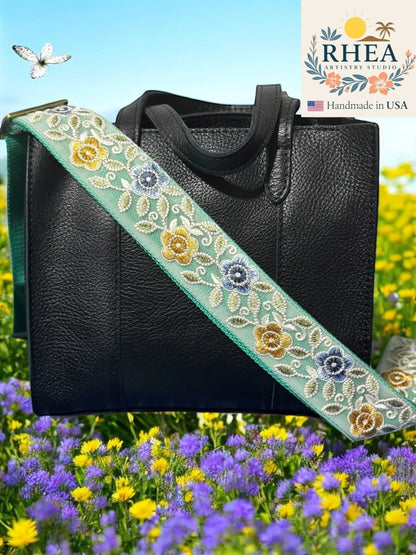 Rhea Artistry Studio mint green crossbody strap with embroidered gold, blue, and white florals, 2-inch width, adjustable length, and brushed brass hardware.