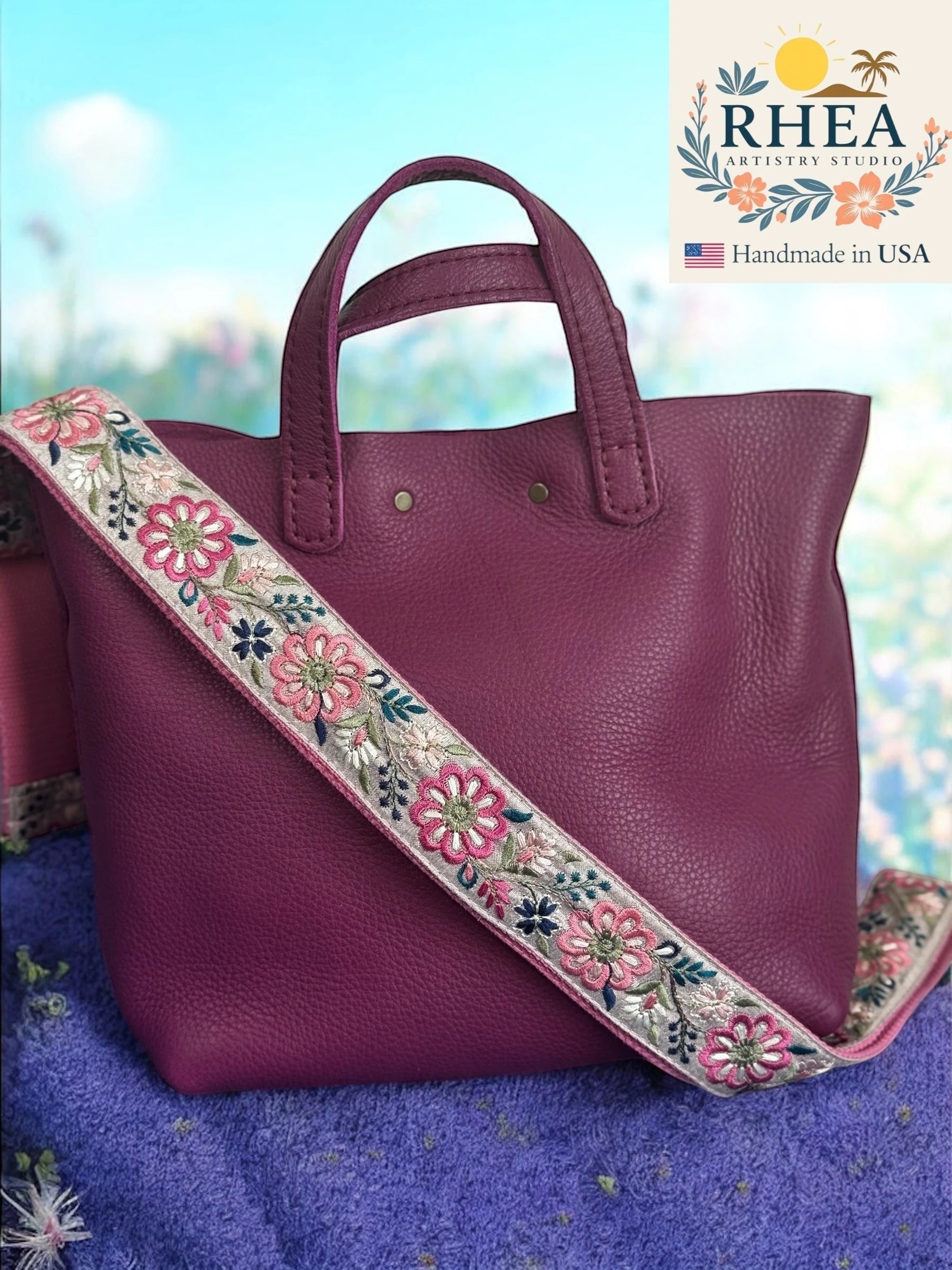 Rhea Artistry Studio 1.5-inch crossbody strap with embroidered pink and white pinwheel flowers on grey backing, adjustable length.