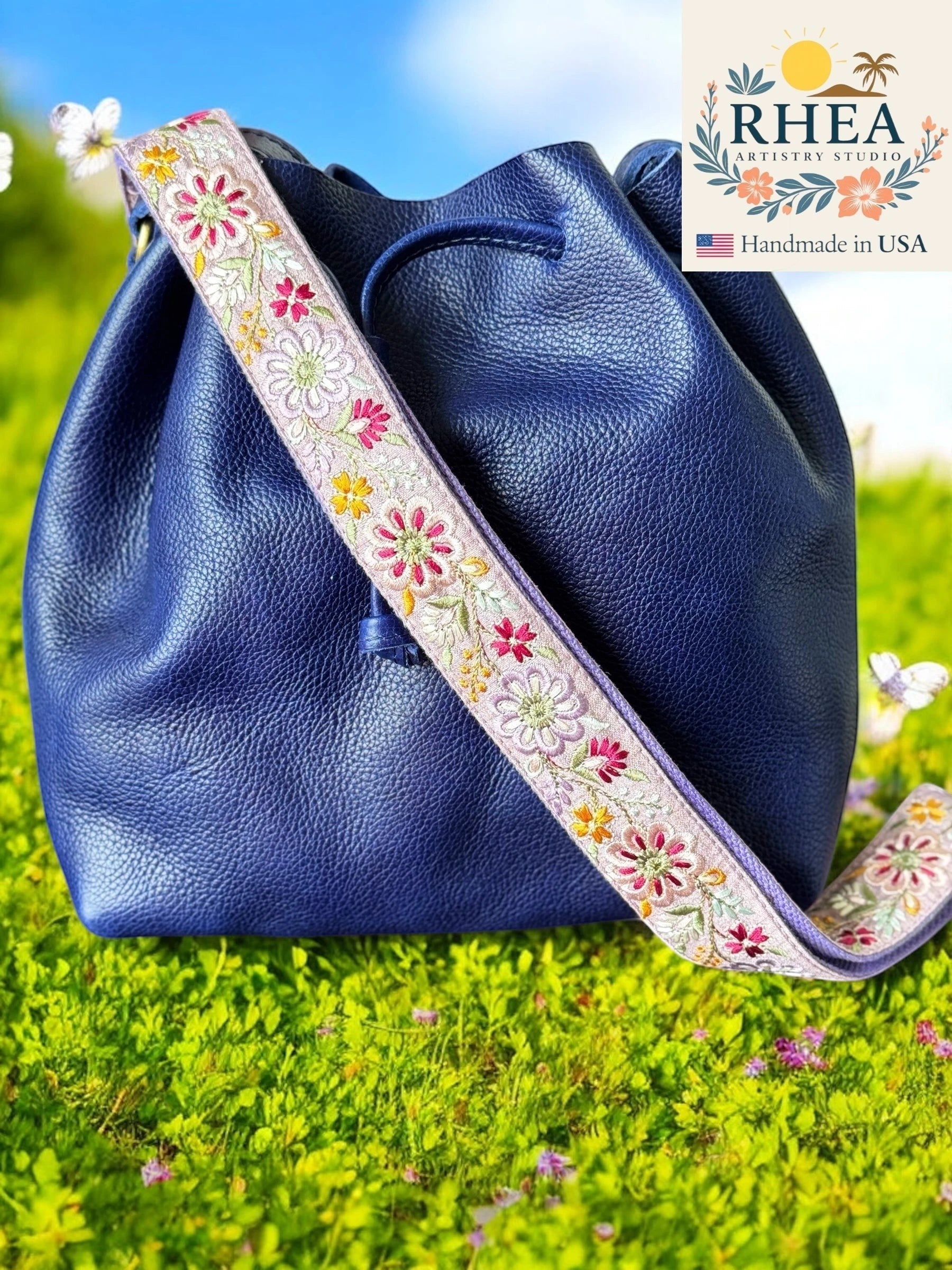 Rhea Artistry Studio 1.5-inch crossbody strap with embroidered pinwheel flowers in pink, yellow, and white on a lavender background.
