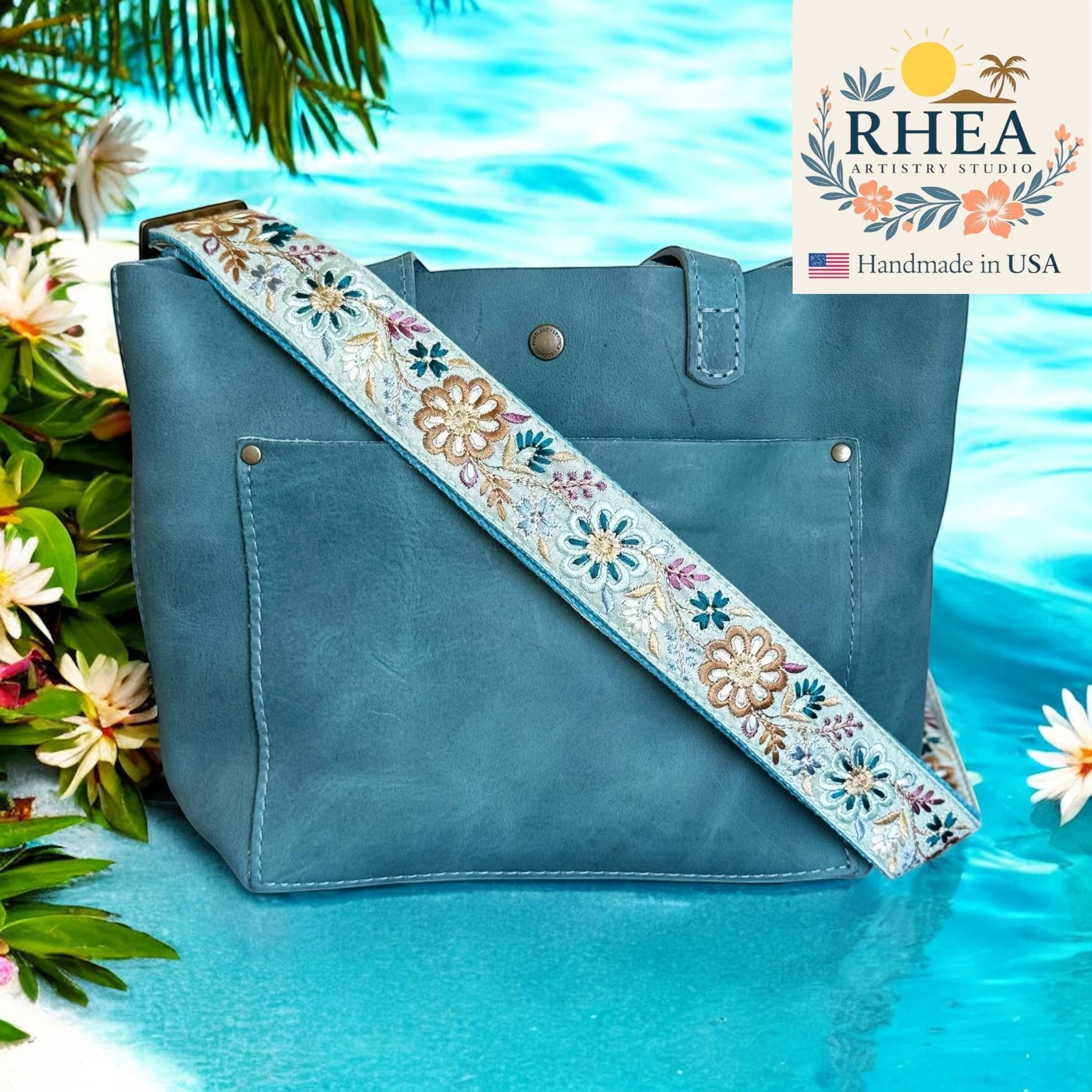 Rhea Artistry Studio light blue crossbody strap with embroidered pinwheel flowers in tan, teal, and purple, 1.5-inch wide with adjustable length.