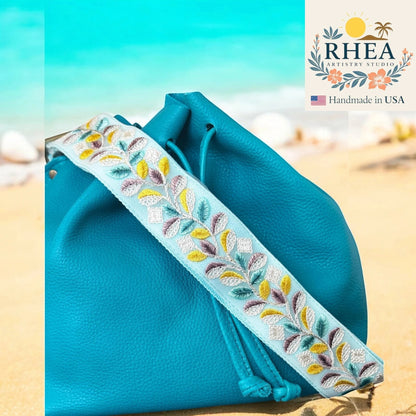 Rhea Artistry Studio light blue embroidered lace crossbody strap with floral vine pattern, adjustable, 2-inch width.