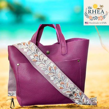 Rhea Artistry Studio 2-inch crossbody strap with embroidered floral lace in white, blue, and orange on a purple leather bag.