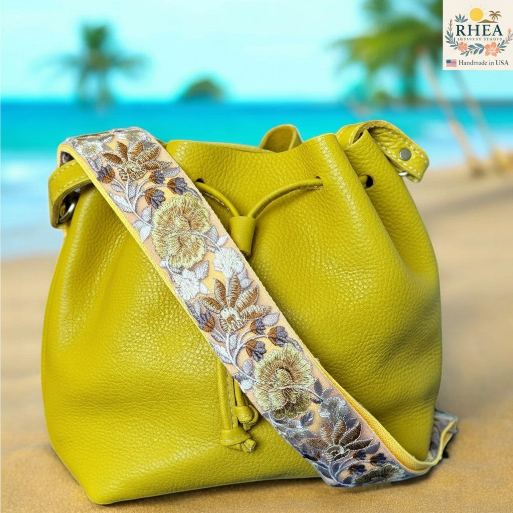 Rhea Artistry Studio 2-inch crossbody strap with rose bloom embroidery in yellow, brown, and grey on a light background.
