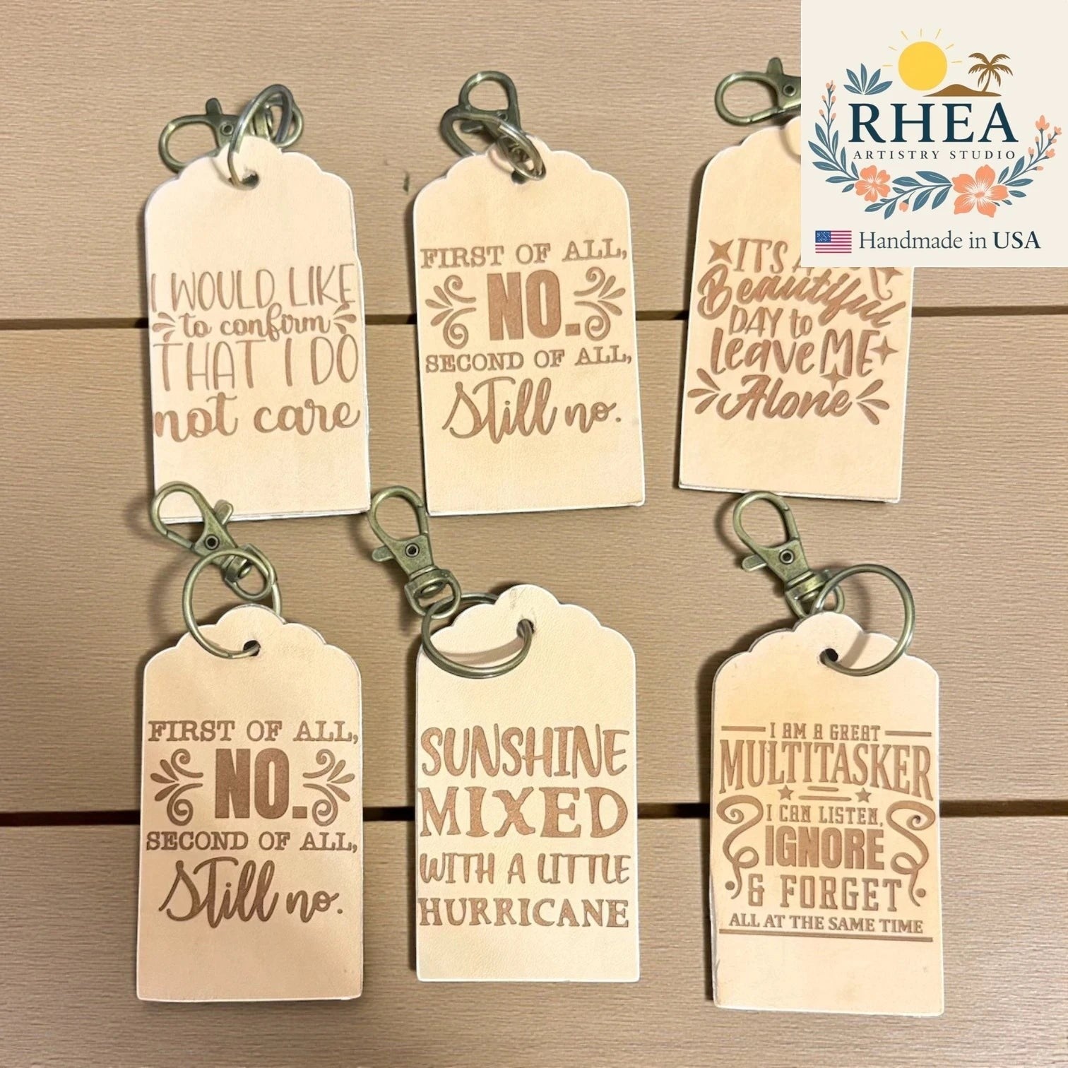 Rhea Artistry Studio collection of six natural vegetable-tanned leather tags with engraved witty quotes and antique brass keychain clips.