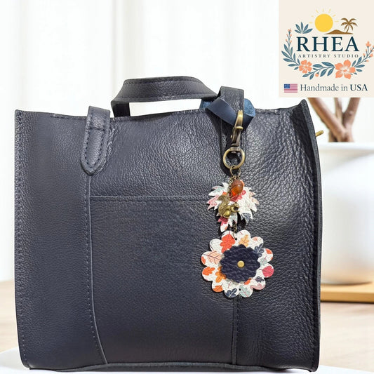 Rhea Artistry Studio navy leather tote bag with a fall-themed leather charm featuring acorn and floral designs.