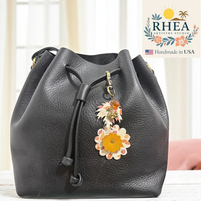 Rhea Artistry Studio black leather bucket bag with a fall-themed leather charm featuring a squirrel and floral design.