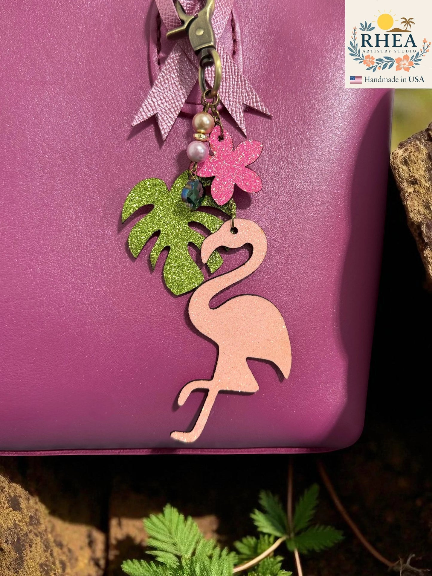 Rhea Artistry Studio pink glitter flamingo charm with green palm leaf, pink flower, pearls, and brass hardware. Handmade in USA.