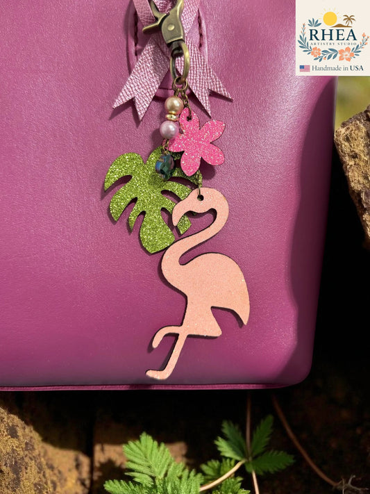 Rhea Artistry Studio pink glitter flamingo charm with green palm leaf, pink flower, pearls, and brass hardware. Handmade in USA.