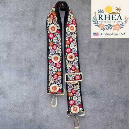 Rhea Artistry Studio black strap with colorful floral embroidery, 2-inch wide, adjustable, with brushed brass hardware.