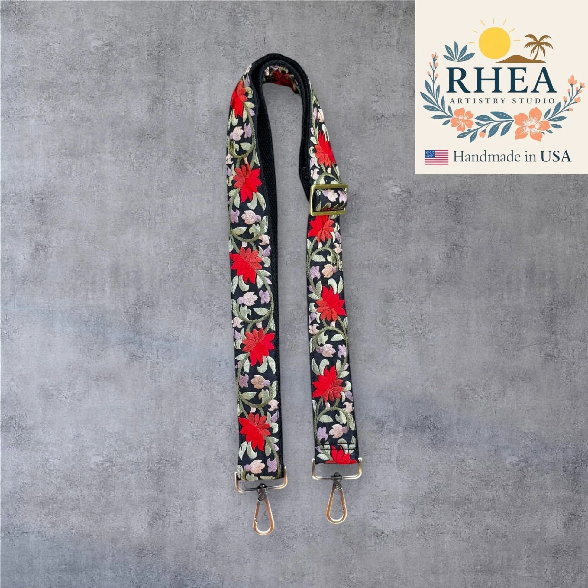 Rhea Artistry Studio black crossbody strap with bold red floral embroidery, adjustable length, and brushed brass hardware.