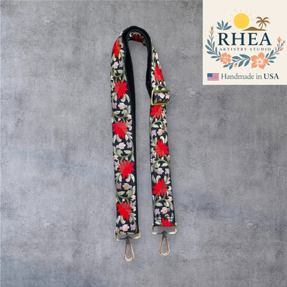 Rhea Artistry Studio black crossbody strap with bold red floral embroidery, adjustable length, and brushed brass hardware.